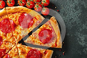 Tasty pepperoni pizza and cooking ingredients tomatoes basil on black concrete background. Top view of hot pepperoni pizza. With