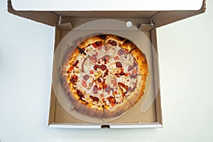 Tasty pepperoni pizza inside open box, white background. Pizza in cardboard box