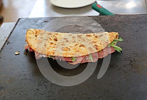 Tasty piadina stuffed with ham and rocket on the hot plate to ba