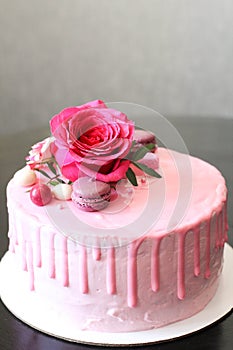 Tasty pink homemade cake decorated by rose and macarons