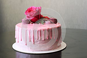 Tasty pink homemade cake decorated by rose and macarons