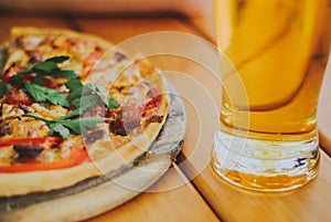 Tasty pizza and glass of beer are on wooden table