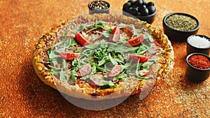 Tasty pizza on a rusty background with spices, herbs and vegetables