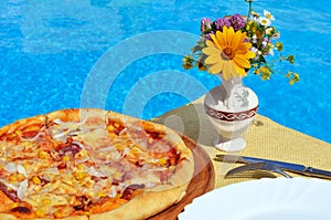 Tasty pizza on the swimming pool background