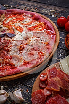 Tasty pizza with a thin red dough on a wooden tray