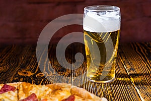 Tasty pizza on wooden table near a glass of beer