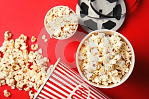 Tasty popcorn and film reel on color background, top view.