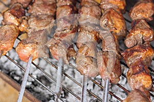 Tasty pork on skewers cooking outdoor on smoldering carbons