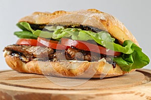 Tasty pork steak sandwich in a ciabatta with tomatos, lettuce