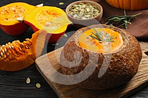 Tasty pumpkin cream soup in bread loaf on table