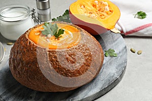 Tasty pumpkin cream soup in bread loaf on table