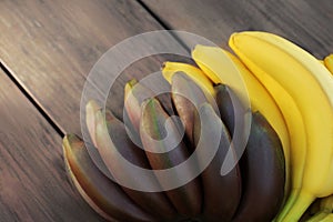 Tasty purple and yellow bananas on wooden table, closeup