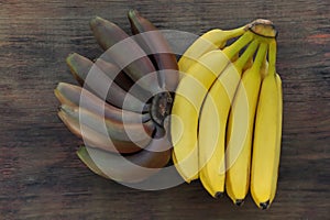 Tasty purple and yellow bananas on wooden table, flat lay photo