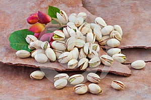 Tasty Raw pistachio nuts with leaves on brown tree rind background