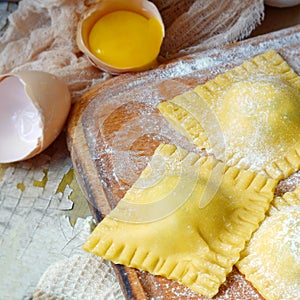 Tasty raw ravioli with ricotta and spinach, with flour and eggs on wooden background. Process of making italian ravioli.