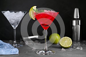 Tasty red alcoholic cocktail in martini glass on grey table