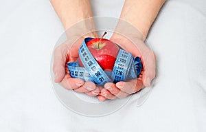 Tasty red apple and tape measure representing slimming and weight loss