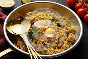 Tasty rice with meat, eggs and vegetables in frying pan near products on black table, closeup