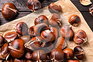 Tasty roasted edible chestnuts on black wooden table, top view