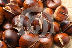Tasty roasted edible chestnuts on parchment, closeup