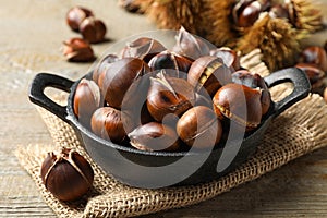 Tasty roasted edible chestnuts on wooden table, closeup