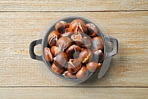 Tasty roasted edible chestnuts on wooden table, top view