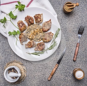 Tasty roasted pieces of pork with mushroom sauce on a white plate with herbs and vintage cutlery wooden rustic background top v