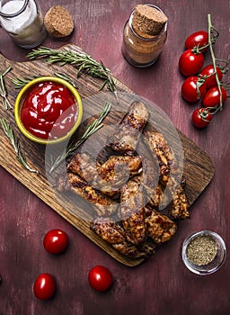 Tasty roasted ribs with spicy sauce and herbs on a cutting board on wooden rustic background top view close