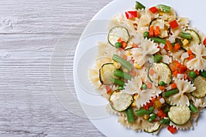 Tasty salad of farfalle pasta with vegetables closeup top view