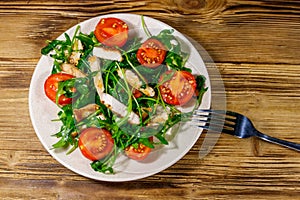 Tasty salad of fried chicken breast, fresh arugula and cherry tomatoes on wooden table. Top view