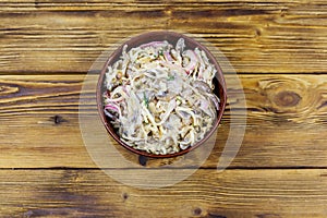 Tasty salad of grated celery root, mushrooms, onions on wooden table. Top view