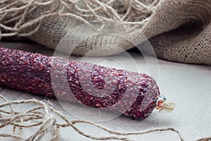 Tasty salami on paper and on a wooden table