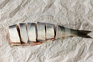 Tasty salted herring cut into large pieces on parchment paper