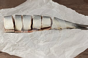 Tasty salted herring cut into large pieces on parchment paper