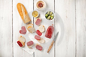 Tasty sandwich, baguette with sausage salami and olives. Fast breakfast or coffe break. Flat lay view