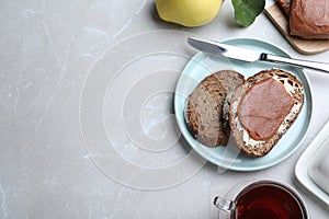 Tasty sandwich with quince paste served for breakfast on light grey marble table, flat lay. Space for text