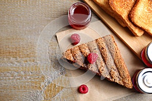 Tasty sandwich with raspberry jam for breakfast on table, flat lay