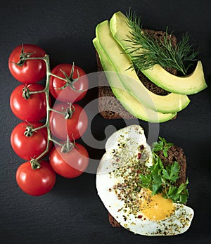 tasty Sandwiches with avocado, fried eggs on a black background