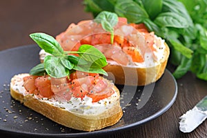 Tasty savory tomato Italian appetizers, or bruschetta, on slices of toasted baguette garnished with basil