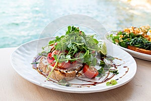 Tasty savory tomatoes on slices of toasted and young green sprouts of peas garnished on wooden table