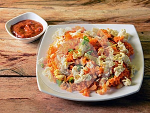 Tasty Schezwan Egg fried rice with tomato sauce served in white plate over a rustic wooden background, Indian cuisine, selective