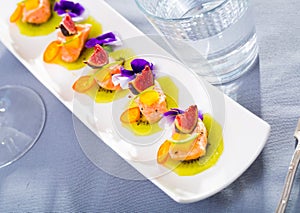 Tasty seafood ceviche from salmon with figs, kiwi and cumquat at plate photo