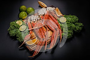 Tasty seafood. Crab claws with greens and limes on black background. Horisontal shot. Close-up. Top view