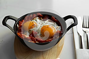 Tasty Shakshouka served in pan on white table, closeup