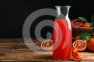 Tasty sicilian orange juice in glass bottle and fruits on wooden table, space for text