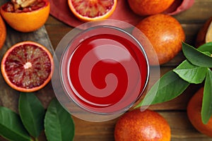 Tasty sicilian orange juice in glass and fruits on wooden table, flat lay