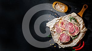 Tasty sliced beef meatloaf with spiec on a cutting board and craft paper. Meat delicacies. Black background. Top view