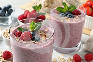 Tasty smoothie with berries, mint and oatmeal on white table, closeup