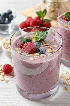 Tasty smoothie with berries, mint and oatmeal on white wooden table