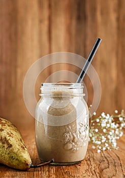 Tasty smoothie with pear and banana in glass on wooden background. Summer cold drink and healthy breakfast.